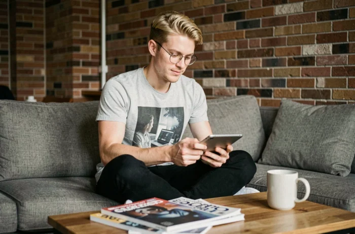 Jeune homme consultant les dernières tendances informatiques sur une tablette dans un appartement urbain moderne