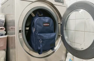 Sac à dos Eastpak marine placé dans le tambour d'un lave-linge avant le lavage en machine